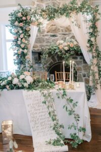 Beautiful sweetheart table at wedding surrounded with lots of flowers, greenery and candles